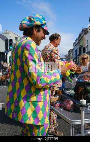 Ballycastle, Regno Unito. 30 agosto 2022. Uomini in abbigliamento colorato che producono animali in mongolfiera in strada al giorno di chiusura della fiera più antica d'Irlanda nella città costiera di Ballycastle sulla costa nord di Antrim, concludendo un fine settimana di contrattazione in banca e un programma ricco di intrattenimento, cucina locale e internazionale alla fiera Ould Lammas. Crediti: Steve Nimmons/Alamy Live News Foto Stock