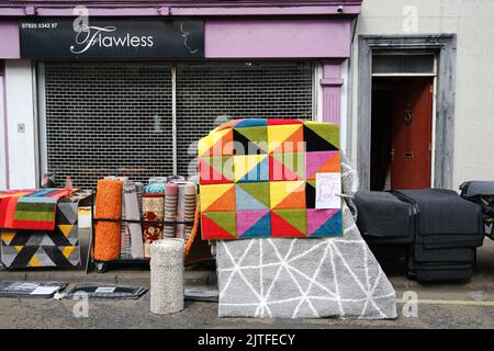 Ballycastle, Regno Unito. 30 agosto 2022. Tappeti e tappeti colorati con motivi geometrici in vendita in strada. Il giorno di chiusura della fiera più antica d'Irlanda nella cittadina balneare di Ballycastle sulla costa nord di North Antrim, che si conclude con un fine settimana di contrattazione in banca e un programma ricco di intrattenimento, cucina locale e internazionale alla fiera di Ould Lammas. Crediti: Steve Nimmons/Alamy Live News Foto Stock