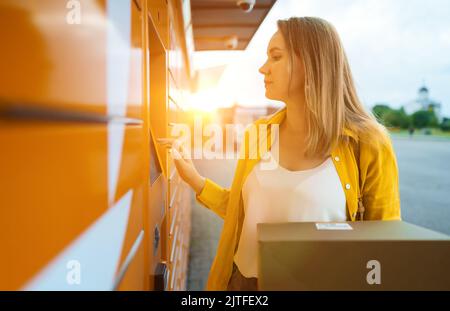 Donna che invia posta tramite terminale automatico self-service. Foto Stock