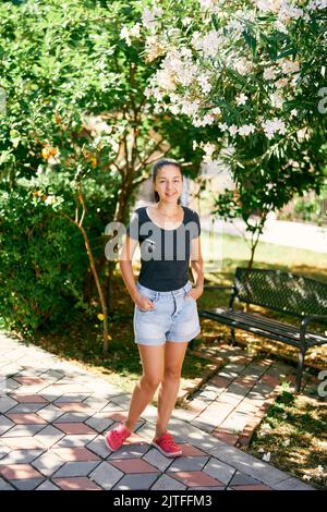 Giovane donna si trova nel parco vicino alla panchina Foto Stock