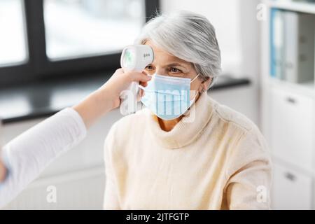 medico con termometro e donna in ospedale Foto Stock