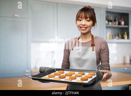 donna felice con biscotti sul vassoio del forno alla cucina Foto Stock