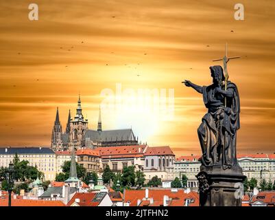 Statua di un santo sul Ponte Carlo che punta verso il Castel di Praga nella Repubblica Ceca. Splendida scena al tramonto a Praga. Foto Stock