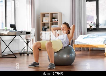 teenage ragazza formazione sulla palla esercizio a casa Foto Stock