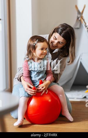 madre e figlia rimbalzano sulla tramoggia a casa Foto Stock