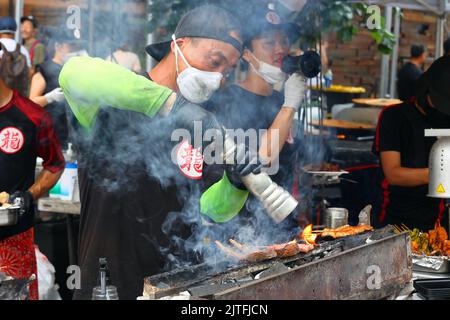 Uno chef Tatsu Yakitori prepara kushiyaki e yakitori su un konro con carbone binchotan in una fiera di strada, New York. Spiedini su una griglia di carbone. Foto Stock