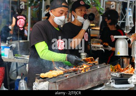 Uno chef Tatsu Yakitori prepara kushiyaki e yakitori su un konro con carbone binchotan in una fiera di strada, New York. Spiedini su una griglia di carbone. Foto Stock