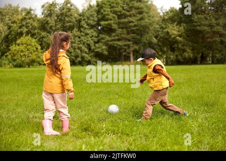 bambini piccoli con la palla che gioca a calcio al parco Foto Stock