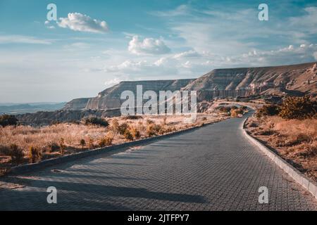 Tortuosa strada di montagna lungo la bellissima costa e mare aperto in estate. Incredibile paesaggio estivo naturale della costa. Concetto di viaggio, trekking, libertà e stile di vita attivo. Filtro vintage a tonalità retrò Foto Stock