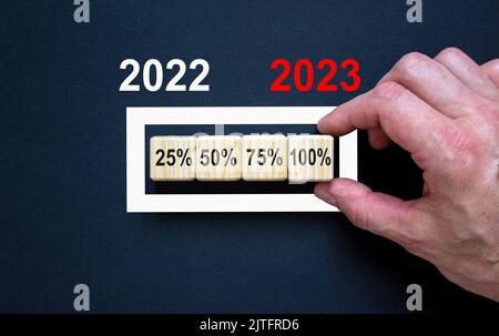 2023 felice anno nuovo simbolo. I cubi di legno simboleggiano il passaggio al nuovo anno 2023. Mano uomo d'affari, numeri 2022, 2023. Splendido sfondo nero. Foto Stock