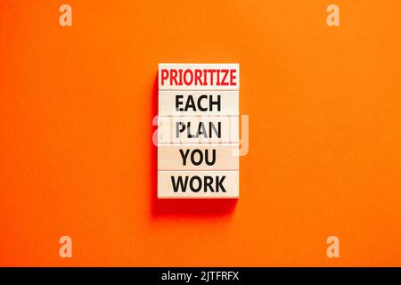 Assegnare la priorità a ciascun piano di lavoro, simbolo. Le parole di concetto danno priorità a ogni piano che lavorate sui blocchi di legno sullo sfondo arancione bello. Priorità aziendale Foto Stock