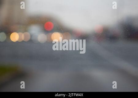 Finestrino dell'auto in un giorno con i blurs colorful luminosi di una strada della città sullo sfondo. Foto Stock