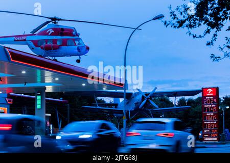 Leverkusen, Germania. 30th ago, 2022. Le auto si ricaricano e passano davanti a una stazione di servizio con un vecchio elicottero sul tetto e uno storico biplano Antonov AN2 accanto ad esso. La notte tra il 31 agosto e il 1 settembre si è conclusa una riduzione temporanea della tassa sull'energia al livello minimo fissato dall'Unione europea. Dal giugno 1 era in vigore fornire aiuti ai consumatori di fronte agli elevati prezzi dell'energia. Allo scadere della misura, il rifornimento di carburante potrebbe diventare di nuovo molto più costoso. Credit: Rolf Vennenbernd/dpa/Alamy Live News Foto Stock