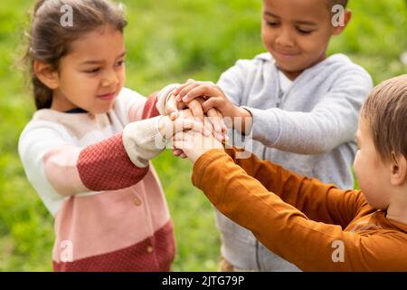 gruppo di bambini che accatastano le mani al parco Foto Stock