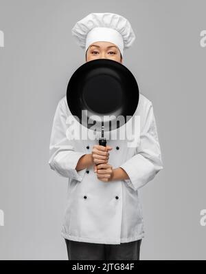 chef femminile che si sbirciava da dietro la padella Foto Stock