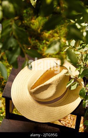 primo piano del cappello di paglia sullo sgabello nel giardino estivo Foto Stock