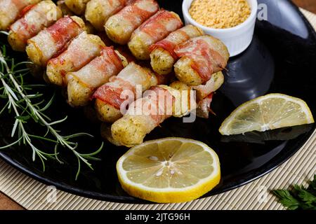 Spiedini di manioca avvolti in pancetta, medaglione di manioca. Foto Stock