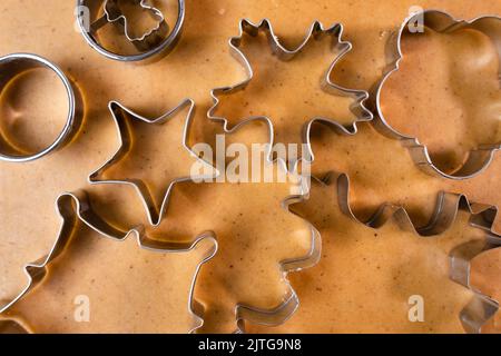 Tagliare i biscotti con muffa metallica dalla pasta frolla. Un metallo si forma sotto forma di fiocchi di neve per fare il pan di zenzero per Natale. Foto Stock