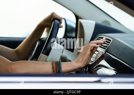 Donna mette mano sul pannello di ventilazione per controllare il flusso d'aria fredda seduto al sedile del conducente in auto nelle calde giornate estive Foto Stock