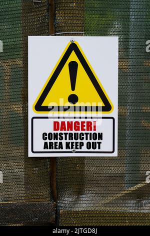 Concetto di sicurezza. Sulla recinzione appende un cartello di avvertimento e un cartello con l'iscrizione - pericolo area di costruzione tenere fuori Foto Stock