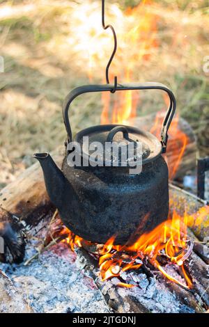 bollitore turistico affumicato sopra il fuoco del campo. Processo di cottura sulla natura. Foto Stock