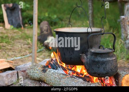 Due bollitori da turismo fumati sopra il fuoco del campo. Processo di cottura sulla natura Foto Stock