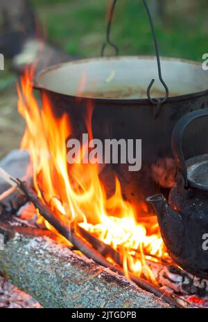 Due bollitori da turismo fumati sopra il fuoco del campo. Processo di cottura sulla natura Foto Stock