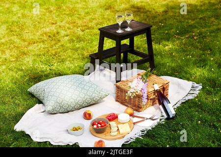 cibo, bevande e cestino da picnic su coperta in erba Foto Stock