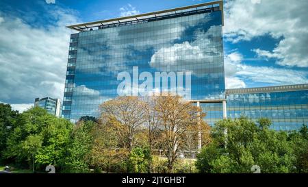 GSK London HQ riflette cielo e nuvole nella facciata a specchio dell'edificio Foto Stock