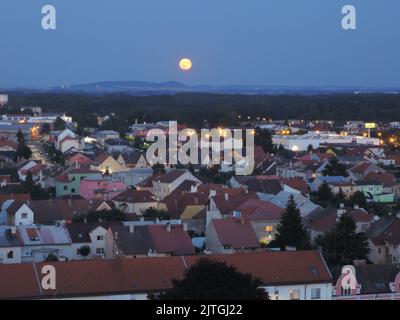 Vista aerea notturna del paesaggio della vecchia città industriale europea durante la luna piena, delle strade scintillanti a lunga esposizione, della città di Nymburk Foto Stock