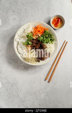 Tradizionale insalata vietnamita di noodle - Bun Bo Nam Bo, con manzo, tagliatelle di riso, erbe fresche, verdure sottaceto e salsa di pesce Foto Stock