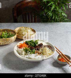 Tradizionale insalata vietnamita di noodle - Bun Bo Nam Bo, con manzo, tagliatelle di riso, erbe fresche, verdure sottaceto e salsa di pesce Foto Stock