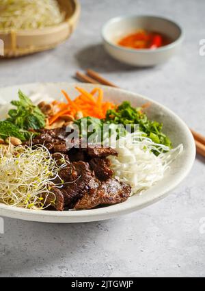 Tradizionale insalata vietnamita di noodle - Bun Bo Nam Bo, con manzo, tagliatelle di riso, erbe fresche, verdure sottaceto e salsa di pesce Foto Stock