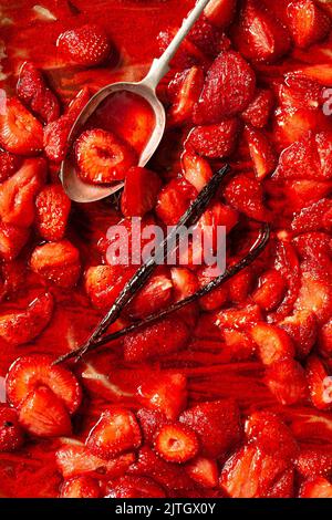 Salsa di fragole su una teglia da tostatura con baccello di vaniglia e un cucchiaio. Foto Stock