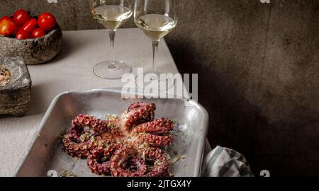 Polpi freschi marinati con spezie, aglio e pomodori su tavola grigia. Foto Stock
