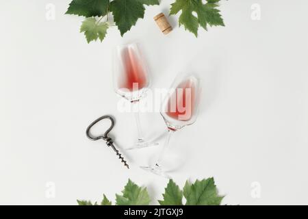Vino rosato in bicchieri e uva. Piatto di bicchieri da vino con vino rosa su sfondo bianco, vista dall'alto. Degustazione di vini, cantina, piatto Foto Stock