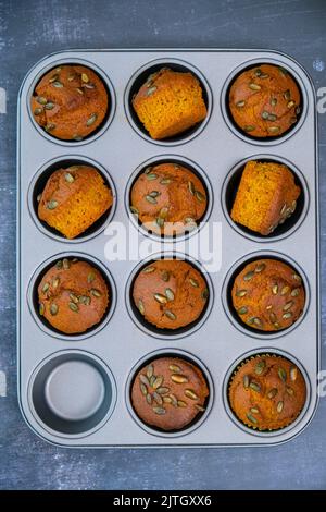 Muffin al pane di zucca ricoperti di semi di zucca in una teglia per muffin. Foto Stock