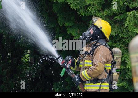 Rouyn-Noranda, Quebec, Canada - giugno 2022 : un pompiere che lotta contro un fuoco domestico durante il giorno, con l'apparecchiatura di protezione respiratoria Foto Stock