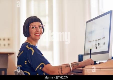 Lei le dà il lavoro tutti i giorni. Ritratto di un giovane stilista alla moda che lavora al computer nel suo studio. Foto Stock