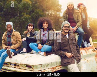 Questi sono i momenti ben ricordare sempre. Ritratto di un gruppo di amici posati intorno ad un vecchio camion in un campo. Foto Stock