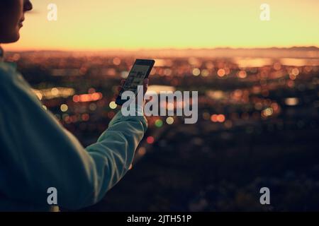 Invio di un testo dall'alto. Donna irriconoscibile che invia un messaggio di testo mentre si trova in piedi su un punto di osservazione. Foto Stock