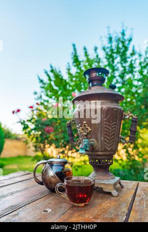 Tè bevendo da un samovar d'annata in giardino Foto Stock