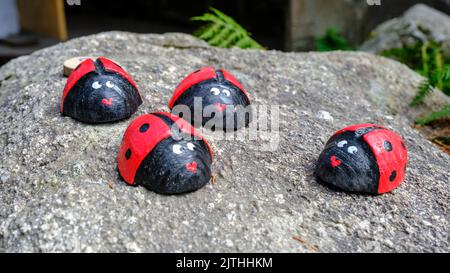 Quattro ladybirds di legno su una pietra. Elemento decorativo da giardino, realizzato a mano. Foto Stock