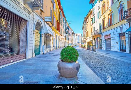 La stretta via curva della Pace, fiancheggiata da edifici storici colorati, Brescia, Italia Foto Stock