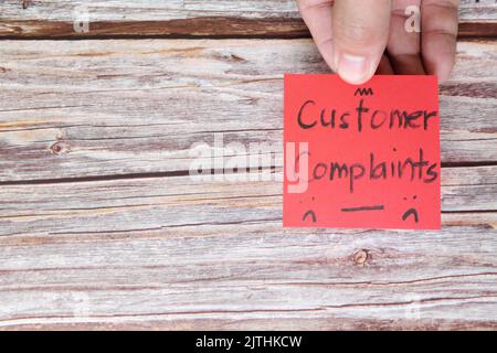 Come gestire il concetto di reclamo del cliente. Mano che tiene nota rossa con le lamentele di parola scritta con spazio di copia. Foto Stock
