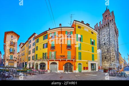 Via Vicolo due Torri storica con ristoranti all'aperto, case colorate e la Torre Pallata in pietra medievale, Brescia, Lombardia, Italia Foto Stock