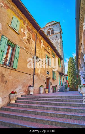 L'antica casa di scabbie e il campanile in pietra medievale della Chiesa di Santa Maria della neve dalla stretta via Santa Maria maggiore, Sirmione, Foto Stock