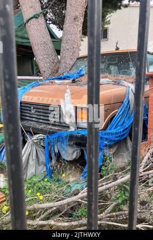 Auto 4x4 abbandonata coperta da rifiuti nel giardino della casa Foto Stock