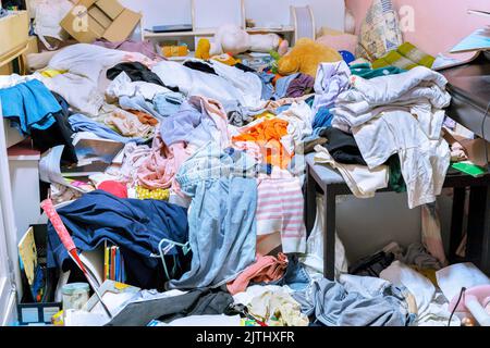 Una stanza stipata di mucchi di vestiti Foto Stock