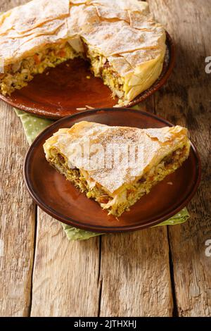 Pastilla marocchina tradizionale appena sfornata o pollo alla basilla primo piano nel piatto sul tavolo. Verticale Foto Stock